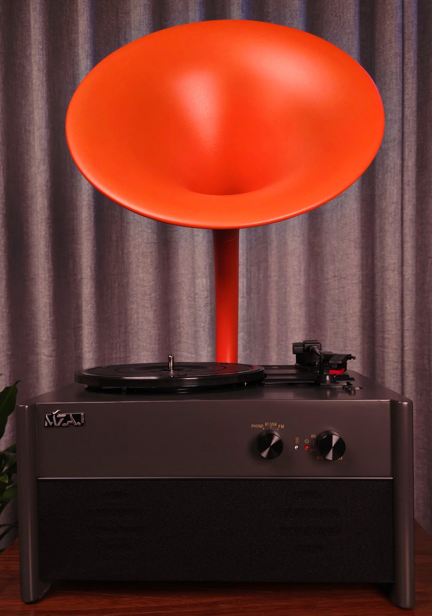 Record player with a large orange speaker against a gray curtain background