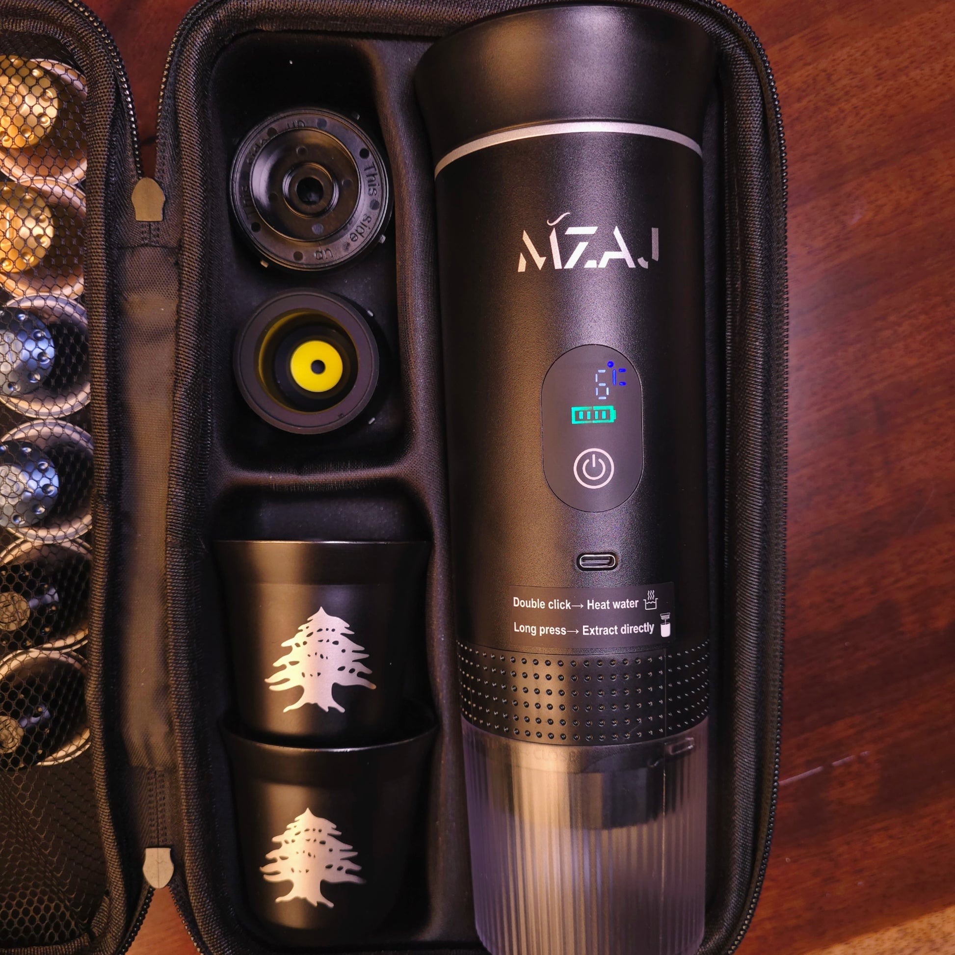 Black MzaJ coffee maker with components in an open case on a wooden surface