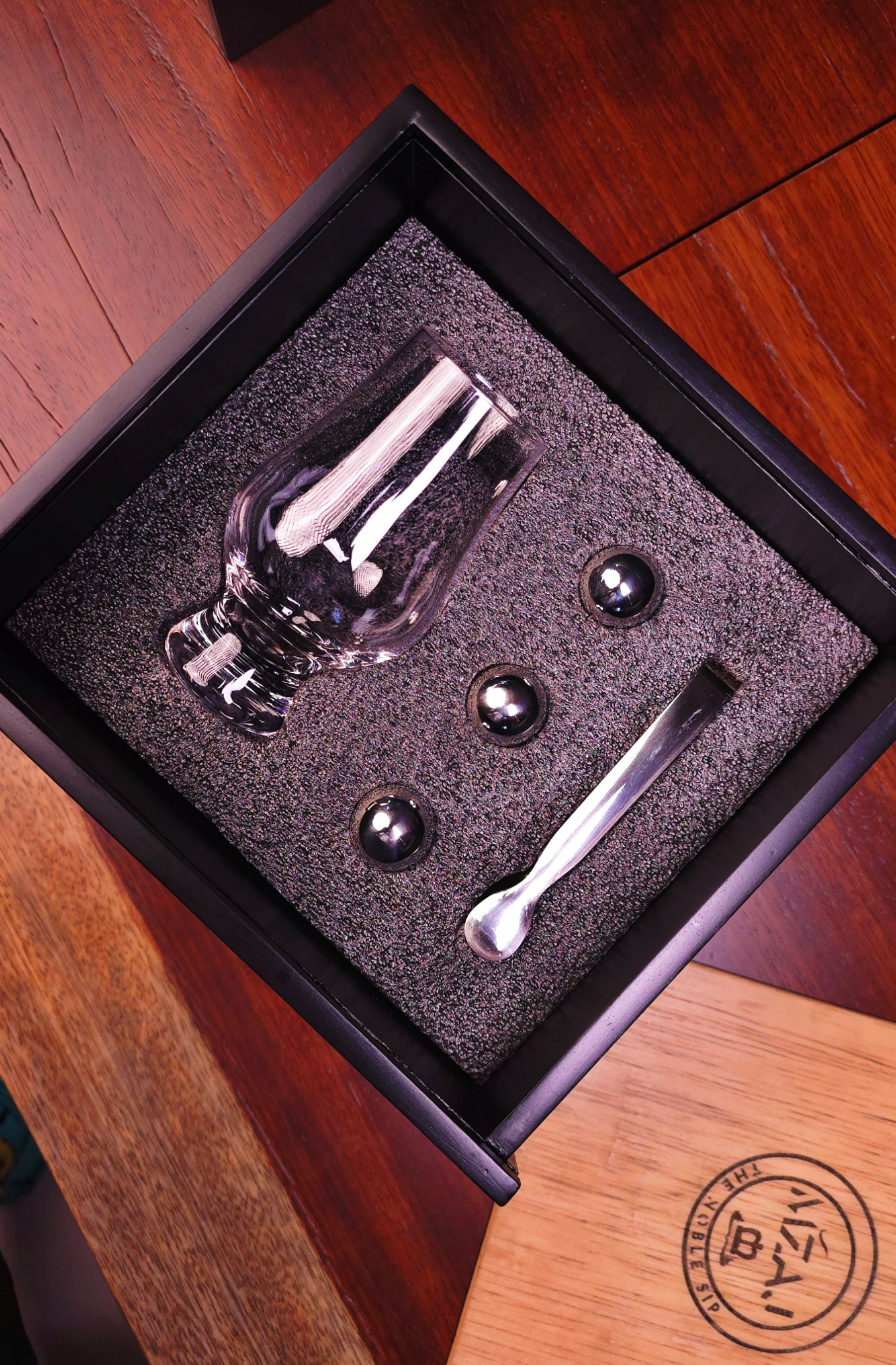 Set of Glencairn glass and tools in a black box on a wooden surface