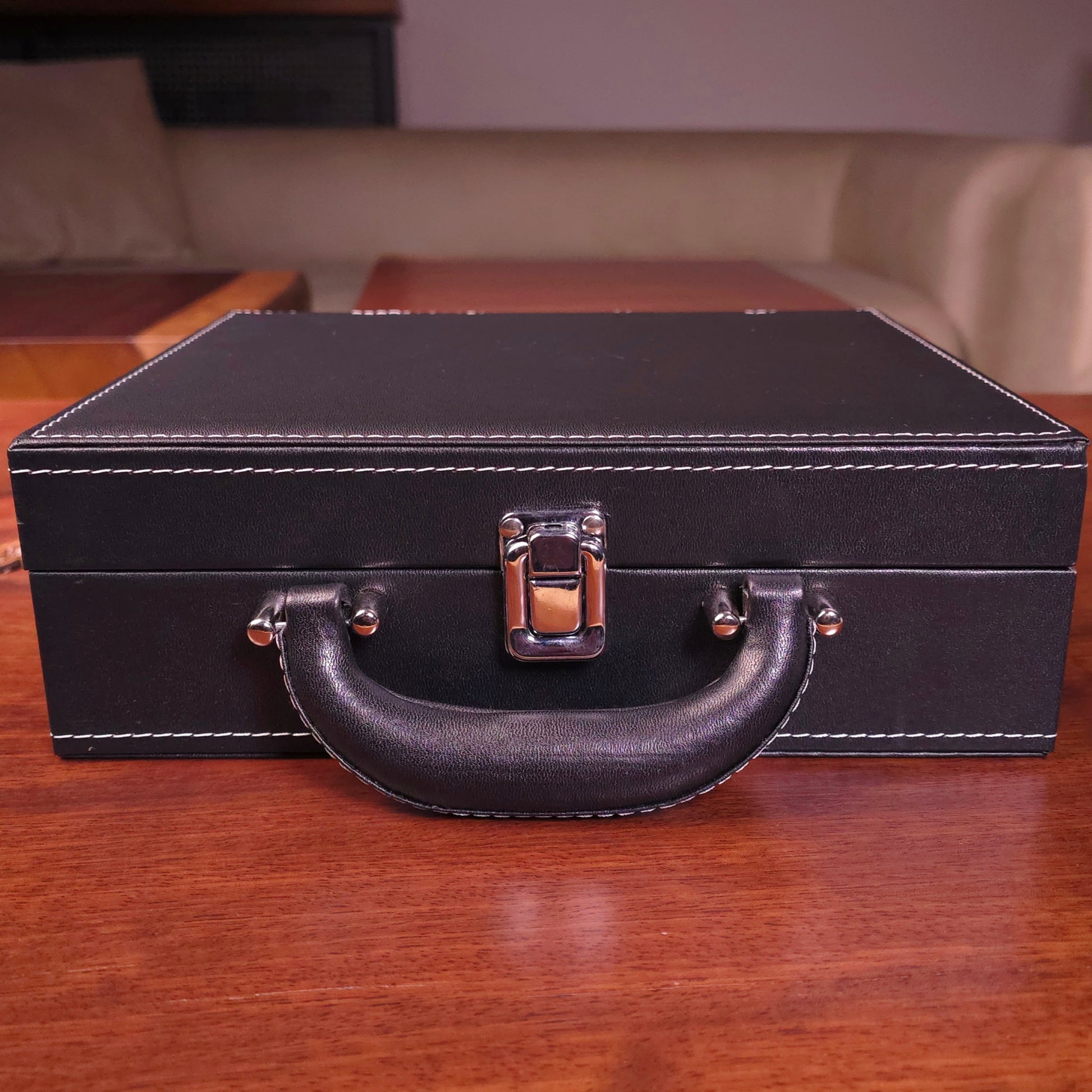 Black leather suitcase with handle on a wooden surface