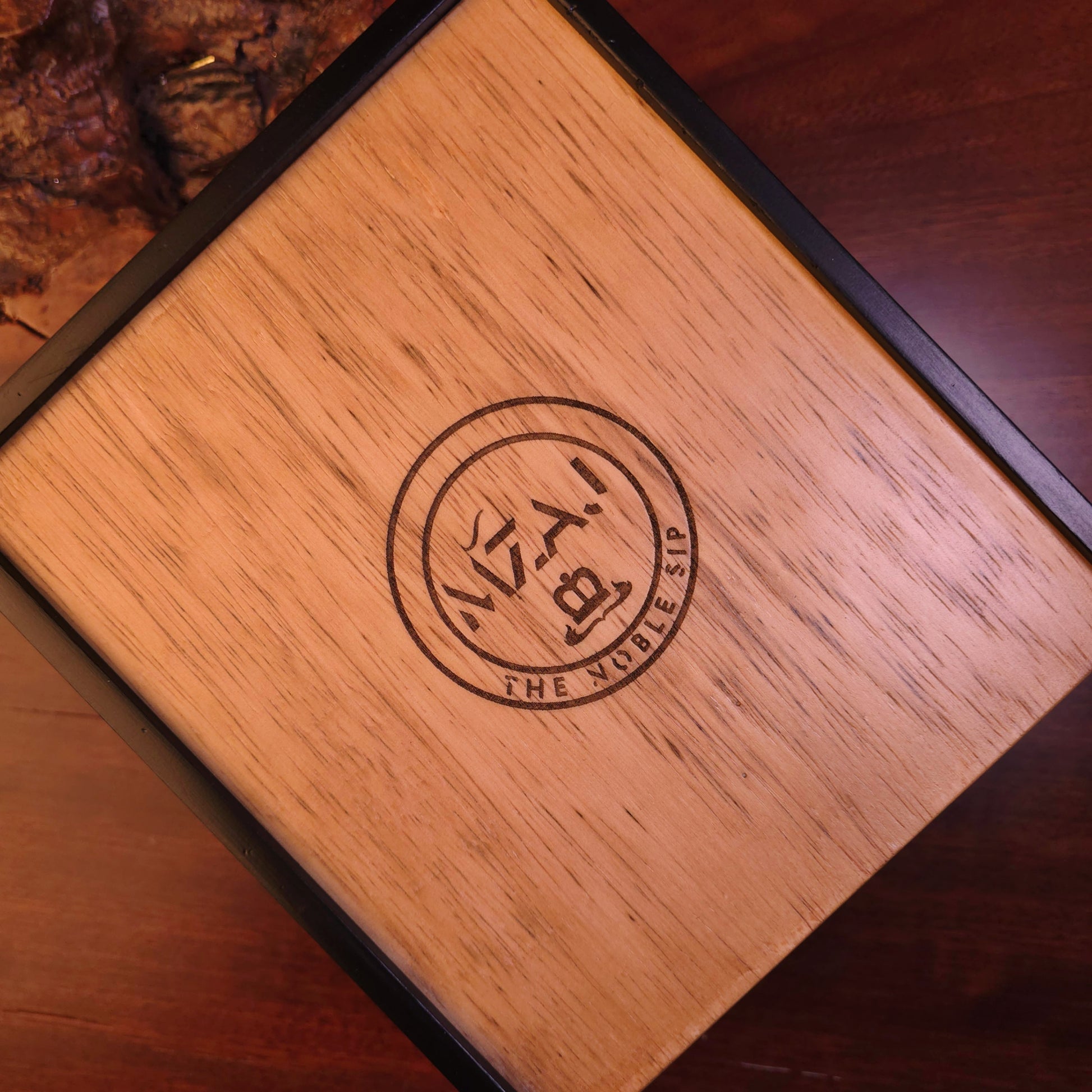 Wooden box with MZAJ logo on a wooden surface
