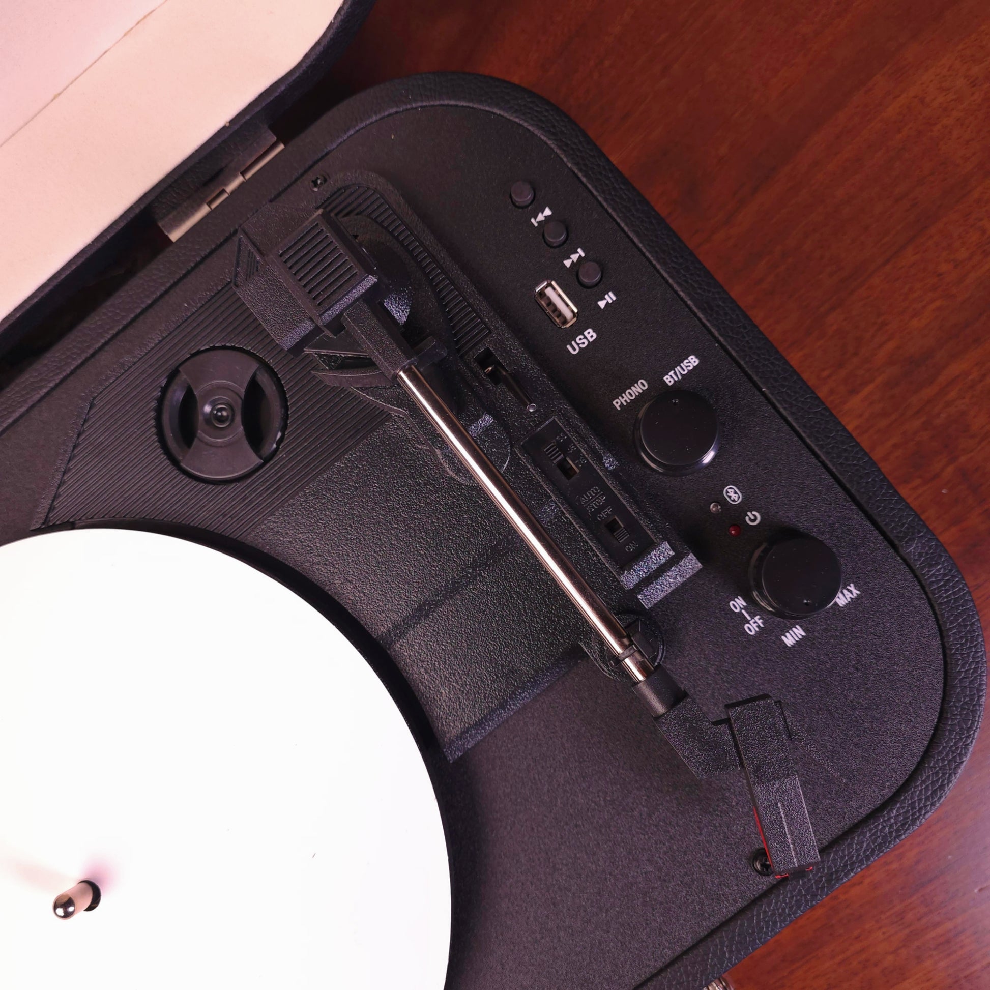 Close-up of a black turntable device with control buttons on a wooden surface