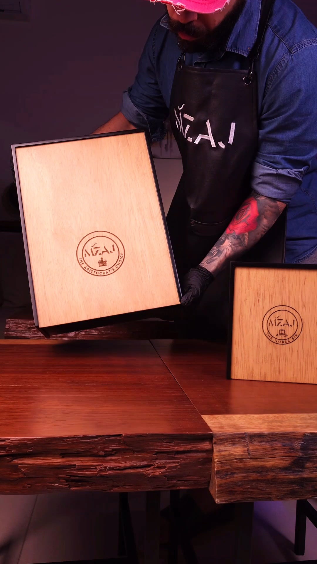 Person holding a wooden box with 'MZAJ' branding on a wooden surface.