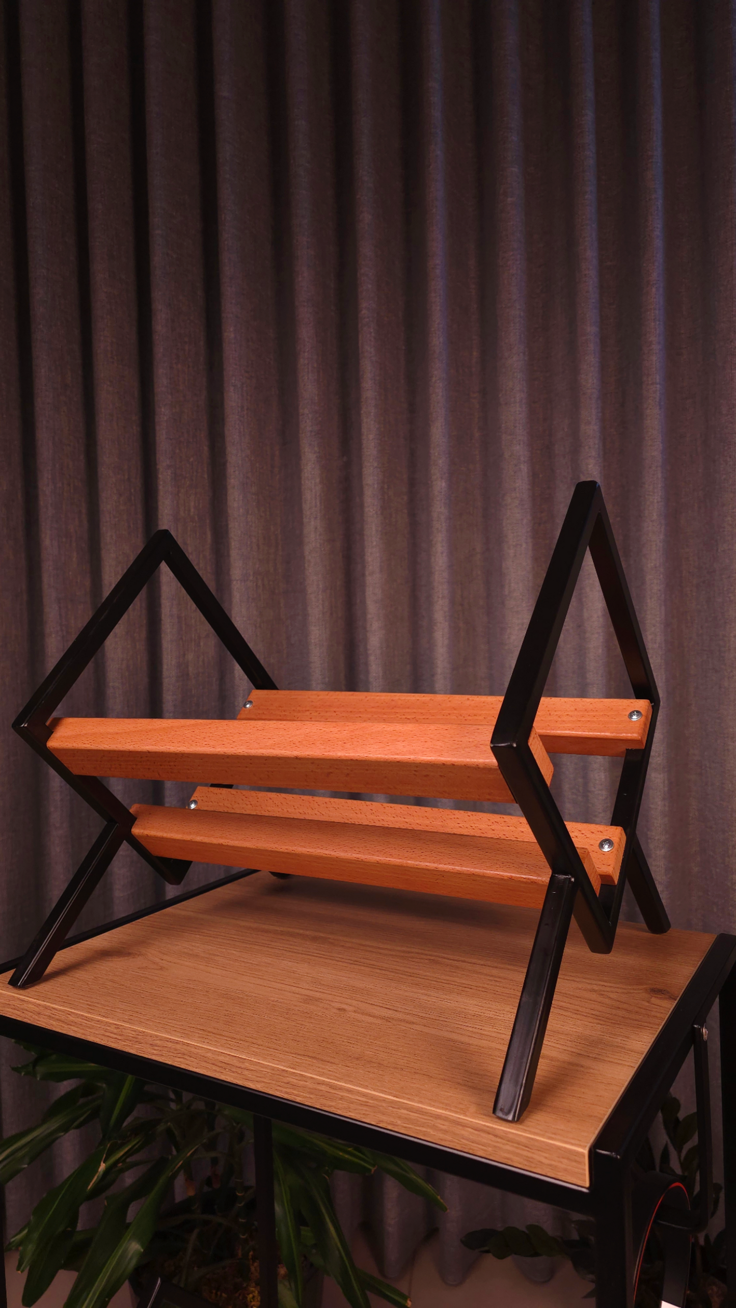 Wooden shelf with black metal frame against a dark curtain background